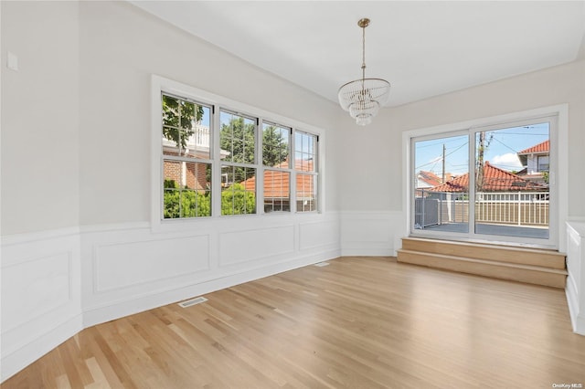 unfurnished dining area featuring wood-type flooring and a notable chandelier