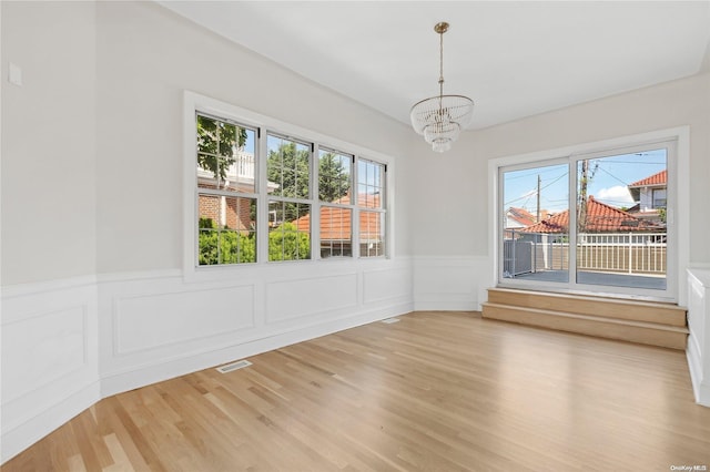 65 W Beech St, Long Beach, NY 11561 - spare room featuring a chandelier, light wood finished floors, wainscoting, and a decorative wall