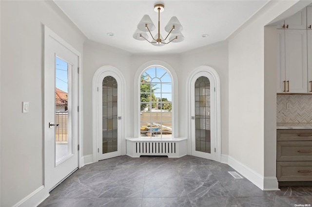 unfurnished dining area with a notable chandelier, radiator heating unit, and french doors