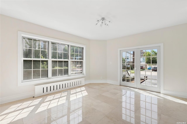 empty room featuring a chandelier, radiator heating unit, and french doors