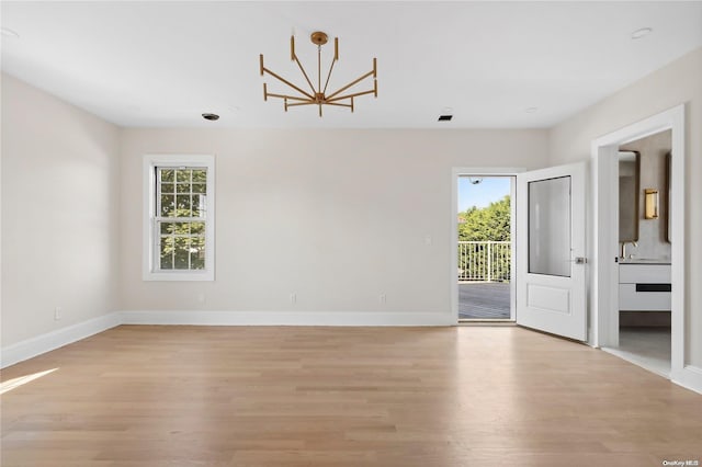 spare room with light wood-type flooring and a notable chandelier