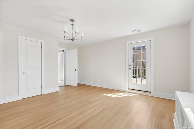 unfurnished room featuring light hardwood / wood-style flooring and a chandelier