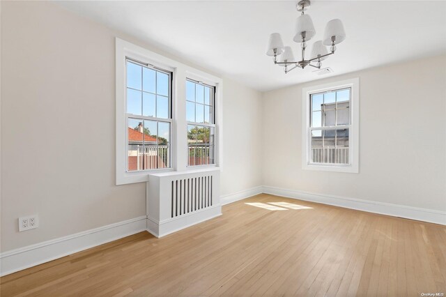 65 W Beech St, Long Beach, NY 11561 - empty room with a chandelier, baseboards, and light wood-type flooring