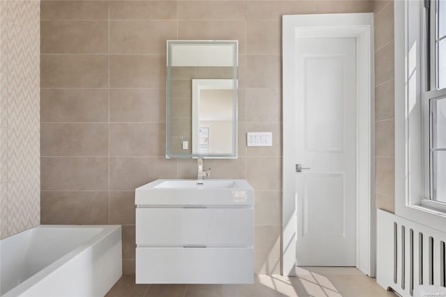 bathroom featuring tile patterned flooring, radiator heating unit, a tub to relax in, and tile walls