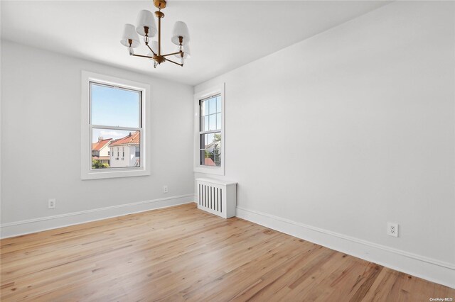 65 W Beech St, Long Beach, NY 11561 - spare room featuring a chandelier, light wood-style flooring, baseboards, and radiator heating unit