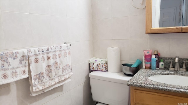 bathroom featuring vanity, tasteful backsplash, toilet, and tile walls