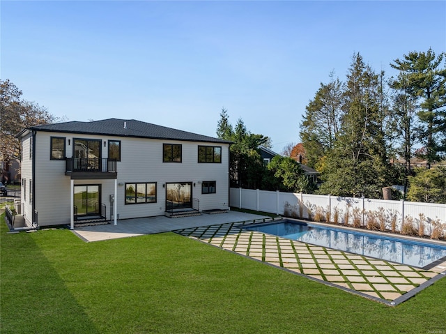 rear view of property with a patio area, a balcony, a yard, and a fenced in pool