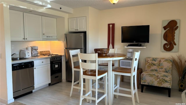 kitchen featuring light wood-type flooring, stainless steel appliances, white cabinetry, and sink