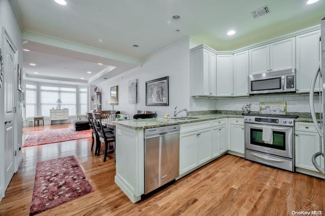 kitchen with white cabinets, light hardwood / wood-style floors, and stainless steel appliances