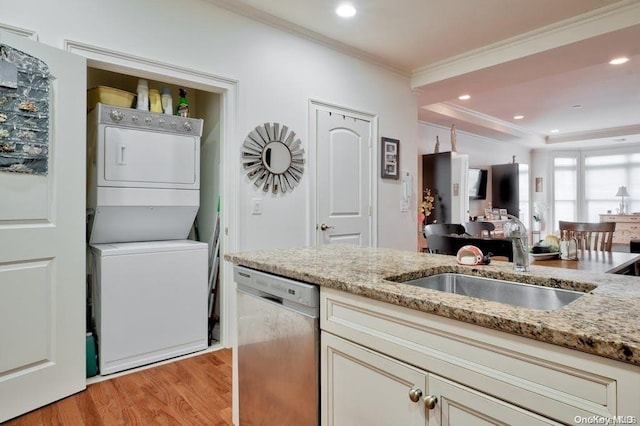 kitchen with dishwasher, light stone countertops, sink, and stacked washer and clothes dryer