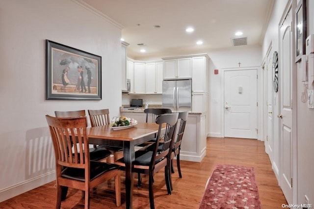 dining room with crown molding and light wood-type flooring