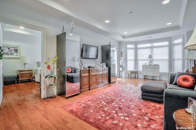 living room with a raised ceiling, crown molding, and light hardwood / wood-style floors