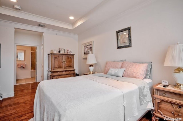 bedroom with hardwood / wood-style floors, crown molding, and connected bathroom