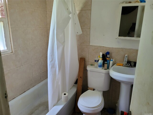 full bathroom with sink, shower / bath combination with curtain, toilet, and tile walls