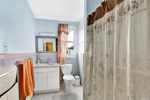 bathroom featuring tile patterned flooring, vanity, tile walls, and toilet