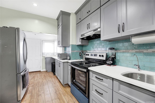 kitchen with decorative backsplash, stainless steel appliances, sink, light hardwood / wood-style flooring, and gray cabinets