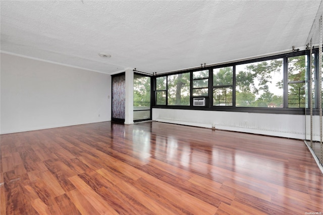 unfurnished room featuring hardwood / wood-style flooring, cooling unit, a textured ceiling, and a baseboard radiator