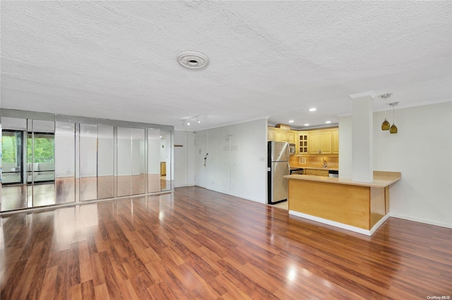 unfurnished living room with hardwood / wood-style flooring, sink, and a textured ceiling