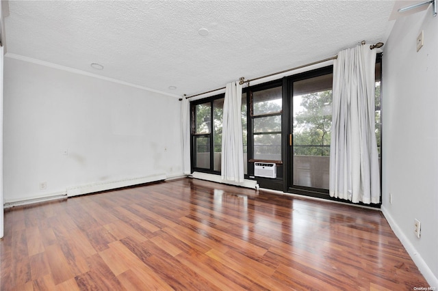 unfurnished room with wood-type flooring, a textured ceiling, baseboard heating, and crown molding