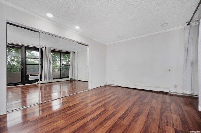 spare room with a textured ceiling, crown molding, baseboard heating, and hardwood / wood-style flooring