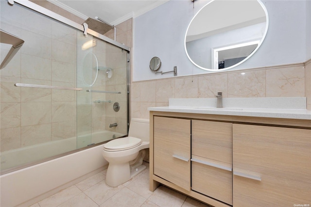 full bathroom with vanity, crown molding, bath / shower combo with glass door, toilet, and tile walls