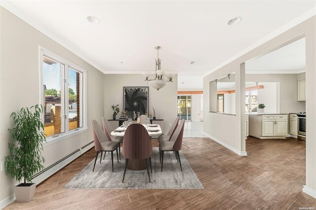 dining area with a wealth of natural light, a notable chandelier, a baseboard heating unit, and light wood-type flooring