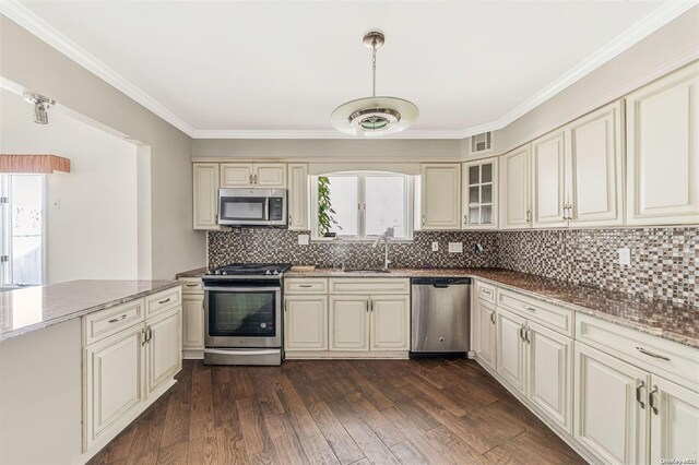 kitchen with sink, dark wood-type flooring, appliances with stainless steel finishes, and cream cabinets