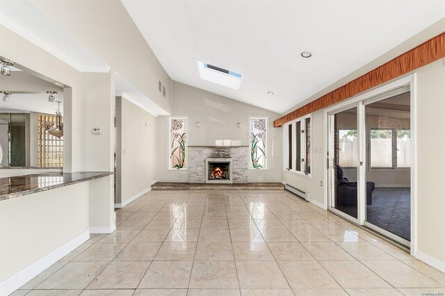 unfurnished living room with a stone fireplace, lofted ceiling with skylight, light tile patterned floors, and a baseboard heating unit