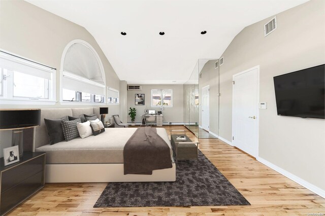 bedroom featuring multiple windows, light hardwood / wood-style flooring, and lofted ceiling