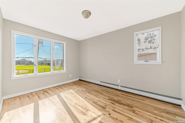 empty room featuring light hardwood / wood-style flooring and a baseboard heating unit