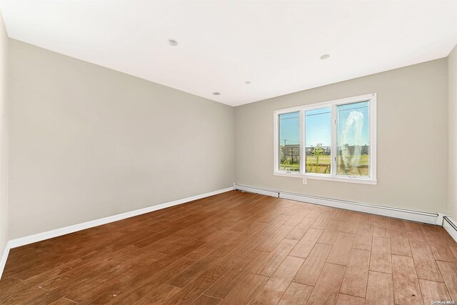 unfurnished room featuring hardwood / wood-style flooring and a baseboard radiator