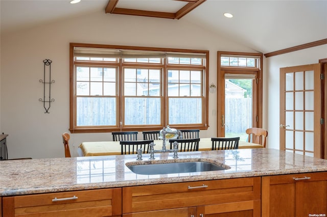 kitchen with light stone countertops, sink, and vaulted ceiling