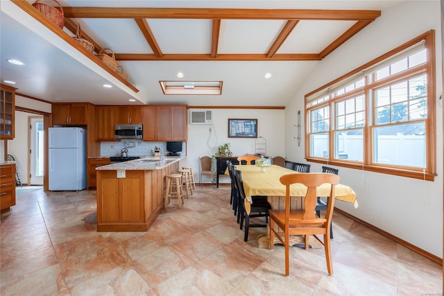 kitchen featuring backsplash, a kitchen island with sink, lofted ceiling with beams, light stone countertops, and white fridge