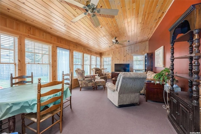 carpeted living room with vaulted ceiling, plenty of natural light, and wood walls