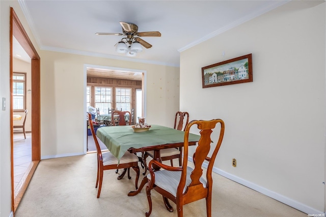 dining space featuring crown molding, ceiling fan, and light colored carpet