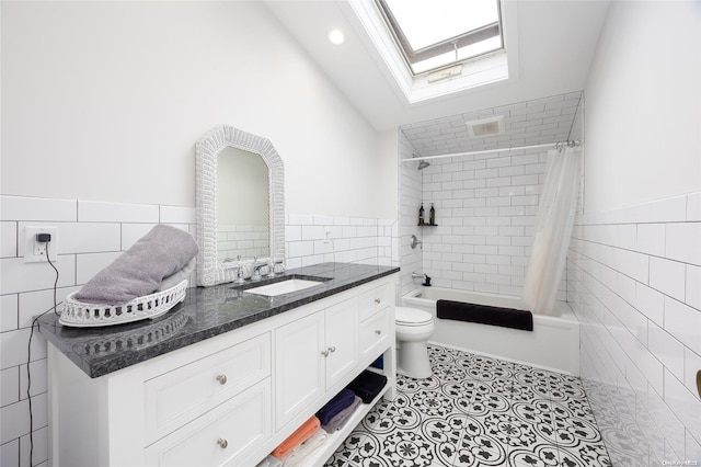 full bathroom featuring vanity, lofted ceiling with skylight, shower / bath combo with shower curtain, tile walls, and toilet