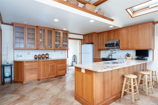 kitchen with backsplash, a skylight, sink, and white refrigerator