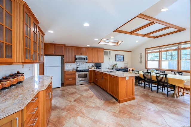 kitchen with light stone countertops, backsplash, stainless steel appliances, sink, and lofted ceiling