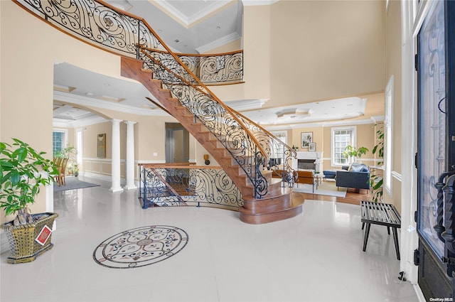 entrance foyer with decorative columns, a wealth of natural light, crown molding, and a high ceiling