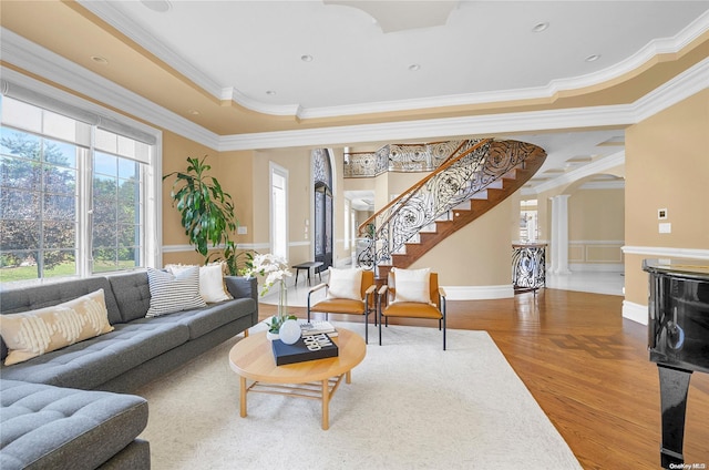 living room with decorative columns, a raised ceiling, hardwood / wood-style flooring, and crown molding