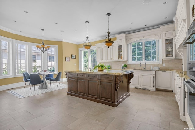 kitchen featuring decorative light fixtures, a center island, tasteful backsplash, and sink