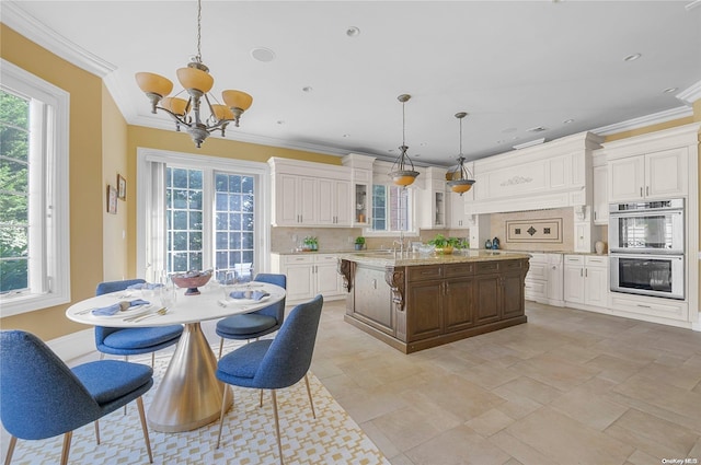 kitchen featuring stainless steel double oven, crown molding, a center island with sink, a notable chandelier, and hanging light fixtures