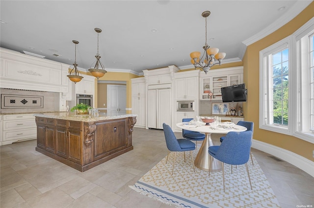 kitchen featuring light stone countertops, hanging light fixtures, built in appliances, crown molding, and a kitchen island with sink