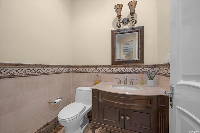 bathroom featuring vanity, toilet, and tile walls