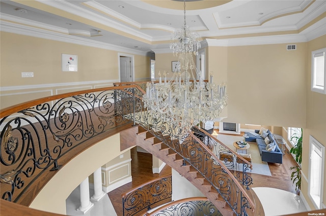 staircase featuring hardwood / wood-style flooring, crown molding, and a notable chandelier