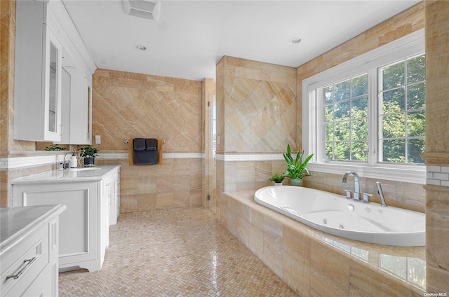 bathroom featuring tile patterned floors, vanity, a wealth of natural light, and tiled bath