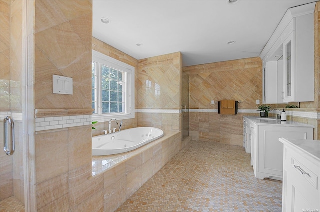 bathroom with tile patterned flooring, shower with separate bathtub, vanity, and tile walls