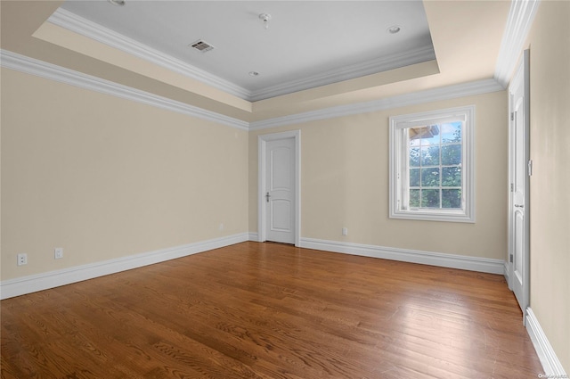 spare room featuring hardwood / wood-style floors, crown molding, and a tray ceiling