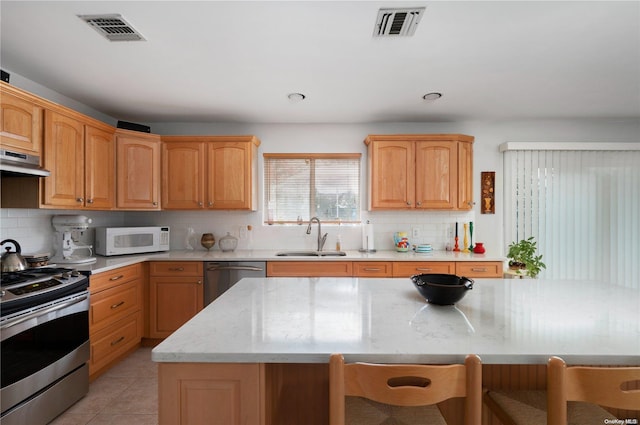 kitchen featuring decorative backsplash, a kitchen breakfast bar, stainless steel appliances, sink, and a center island