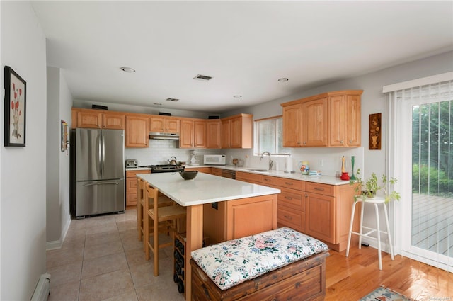 kitchen featuring a kitchen bar, a center island, stainless steel refrigerator, and a healthy amount of sunlight